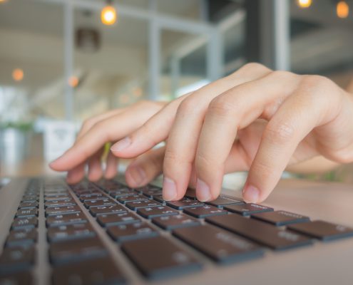 Closeup of business woman hand typing on laptop keyboard
