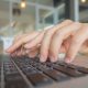 Closeup of business woman hand typing on laptop keyboard